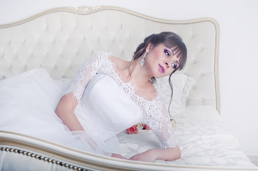 Bride in Lace Wedding Dress on Elegant White Bed