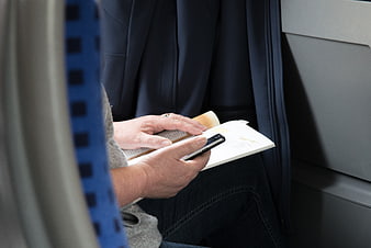 Senior woman reading book and using smartphone on train
