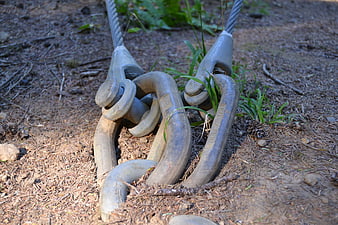Heavy metal shackles and steel cables on forest ground