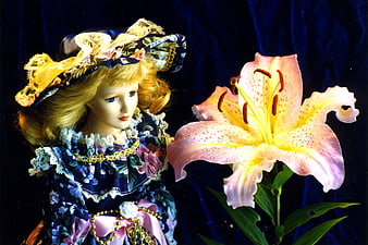 Vintage doll in floral dress with large pink lily