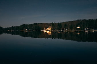 Serene Night Lake with Starry Sky and Glowing House Reflection