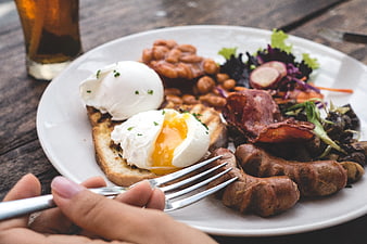Close-up of hearty brunch plate with poached eggs, bacon, and sausage