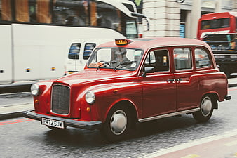 Classic red London taxi driving on city street