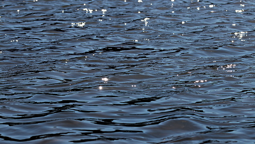 Close-up of dark blue rippling water with sunlight reflections