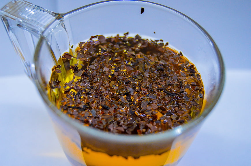 Close-up of loose leaf tea steeping in a glass cup