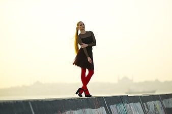 Fashionable Woman in Red Tights Standing on Concrete Wall