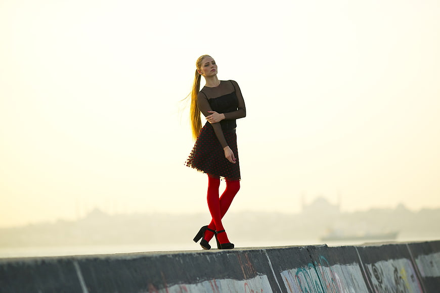 Fashionable Woman in Red Tights Standing on Concrete Wall