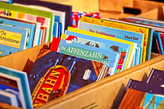 Close-up of colorful used children's books in a cardboard box