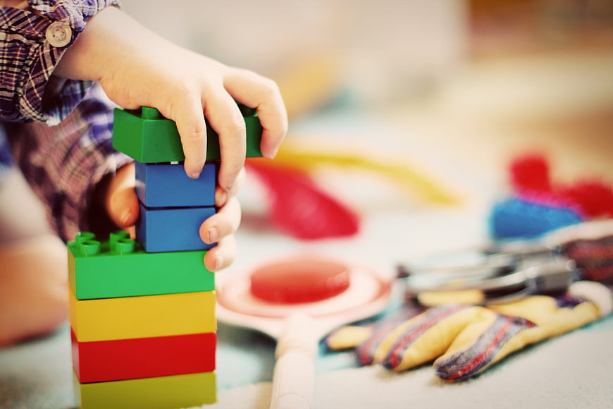 Child's Hands Stacking Colorful Building Blocks