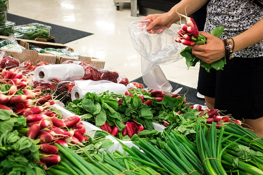 Woman buying fresh radishes and green onions at a grocery store