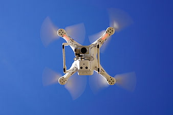 White Quadcopter Drone Flying Against Blue Sky