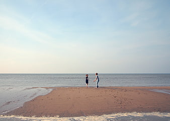 Two children playing on a sandy beach spit at low tide