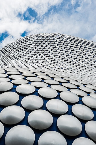 Modern silver dome architecture with circular patterns against blue sky