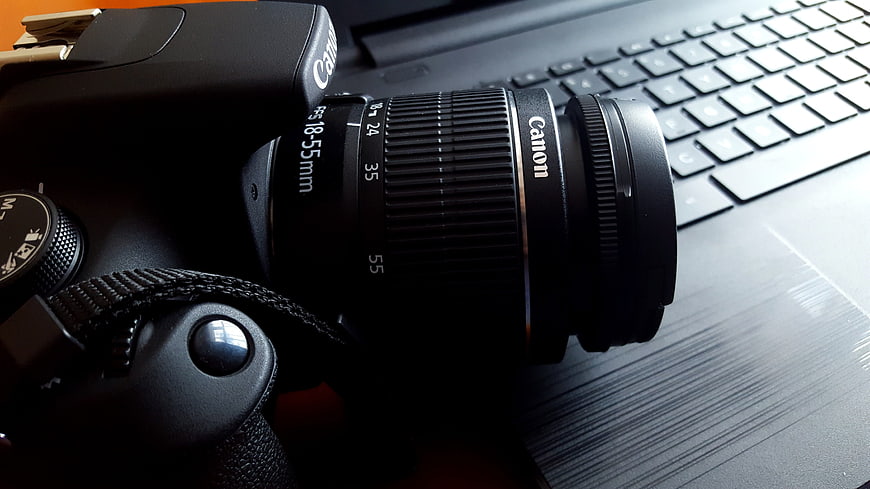 Canon DSLR camera with 18-55mm lens resting on a laptop keyboard