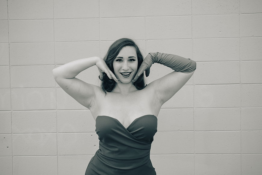 Vintage style woman in strapless dress posing against brick wall
