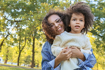 Happy mother holding young daughter in autumn park