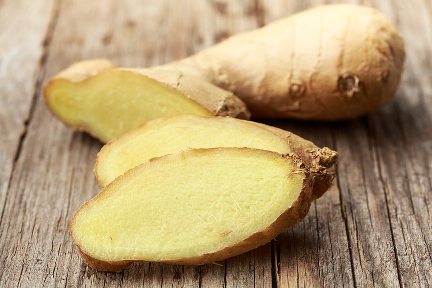 Fresh sliced ginger root on rustic wooden background