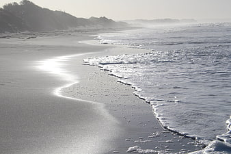 Serene misty beach landscape with gentle waves and dunes