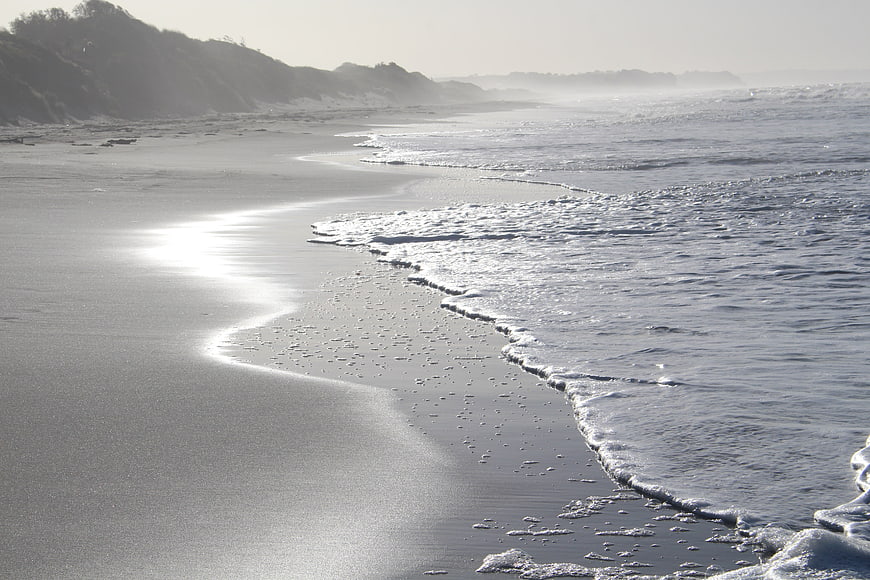 Serene misty beach landscape with gentle waves and dunes