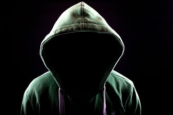 Anonymous figure in green hoodie with shadowed face