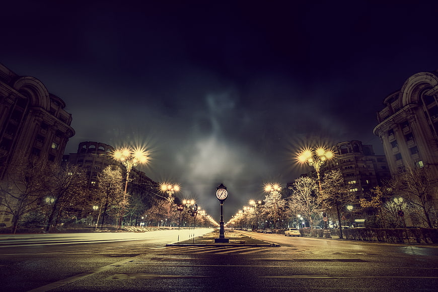 Vintage street clock on empty city avenue at night