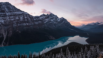 Turquoise mountain lake reflecting snow-capped peaks at sunset