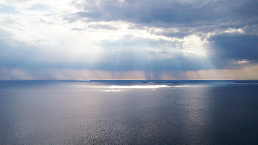 Dramatic Sun Rays Over Calm Ocean Horizon