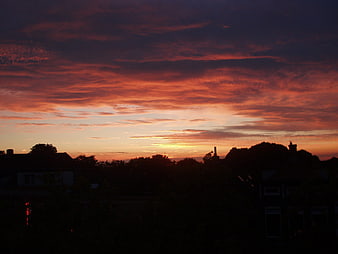Dramatic fiery sunset over suburban rooftops silhouette