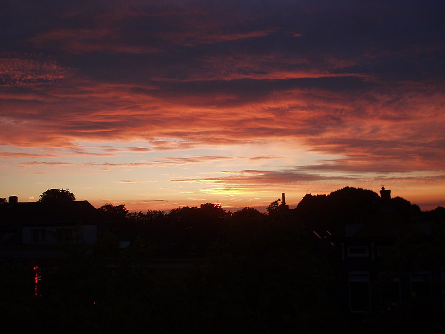 Dramatic fiery sunset over suburban rooftops silhouette