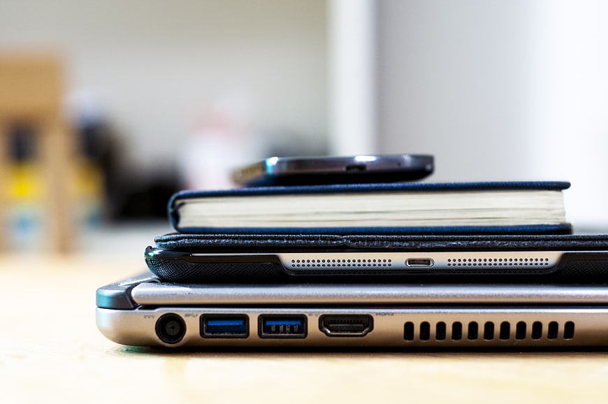 Stack of laptop, tablet, notebook, and smartphone on desk