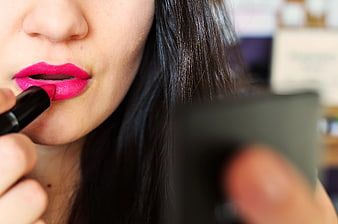 Close-up of woman applying bright pink lipstick