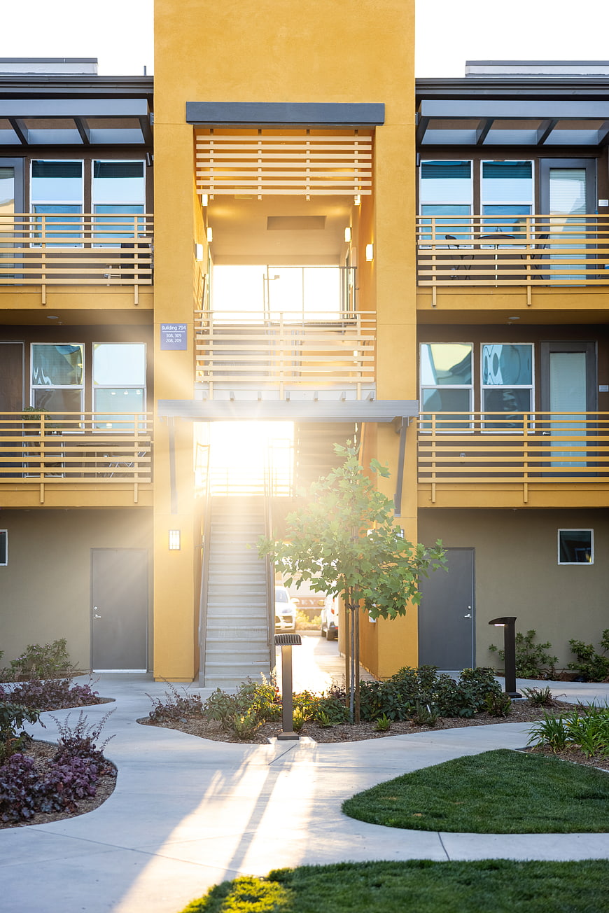 Modern Yellow Apartment Building Exterior with Sun Flare