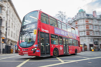 Red double-decker bus driving through London street