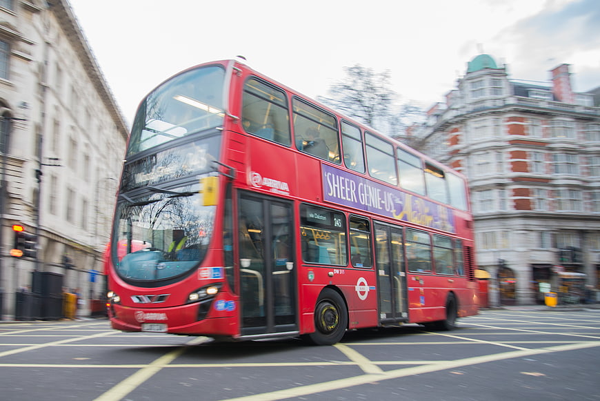 Red double-decker bus driving through London street