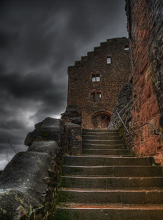 Dramatic stone castle ruins with stairs under stormy sky