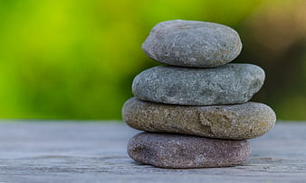 Stacked smooth stones on wooden surface with green background