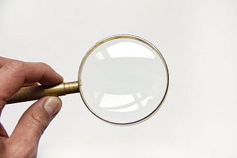 Hand holding brass magnifying glass on white background