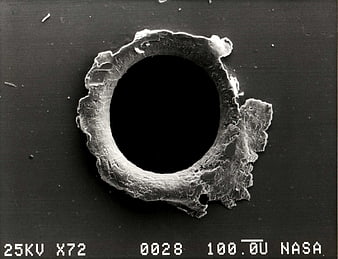 Microscopic view of space debris impact hole on surface