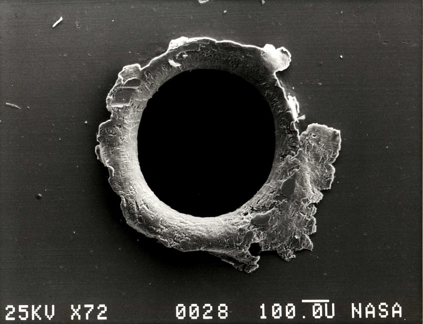 Microscopic view of space debris impact hole on surface