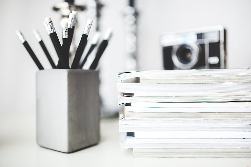 Stack of notebooks and pencils on a white desk