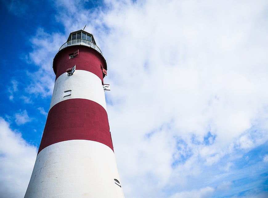 Red and White Lighthouse Against Blue Sky with Clouds