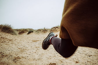 Low angle shot of running shoes on sandy dunes