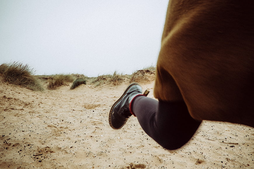 Low angle shot of running shoes on sandy dunes
