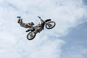 Motocross Rider Performing Aerial Stunt Against Cloudy Sky