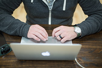 Man Typing on Laptop at Wooden Desk