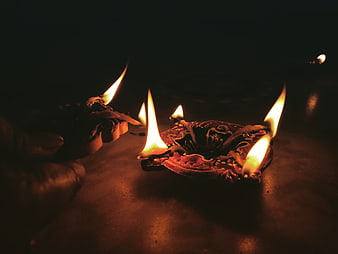 Traditional clay oil lamps with flames in dark setting