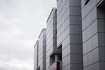 Modern gray building facade with geometric lines and overcast sky