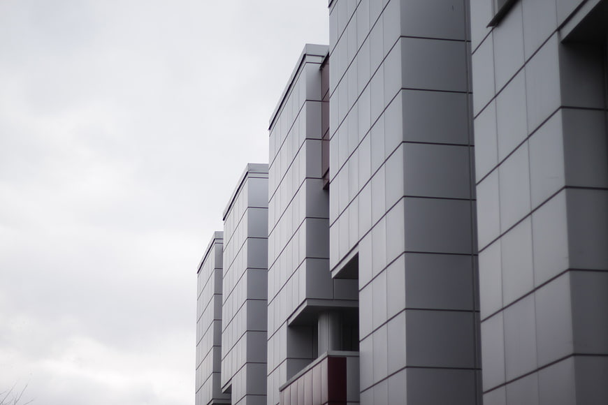 Modern gray building facade with geometric lines and overcast sky
