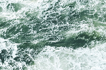 Aerial view of turbulent green ocean waves with white foam
