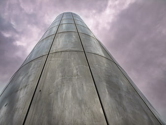 Low angle view of modern steel tower against moody purple sky